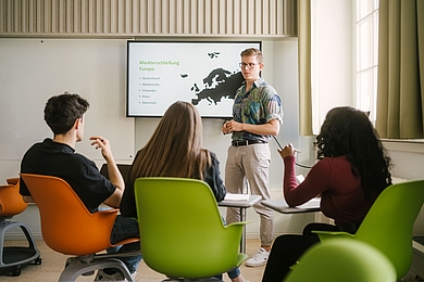 Student hält vor einer Gruppe von Studierenden eine Präsentation